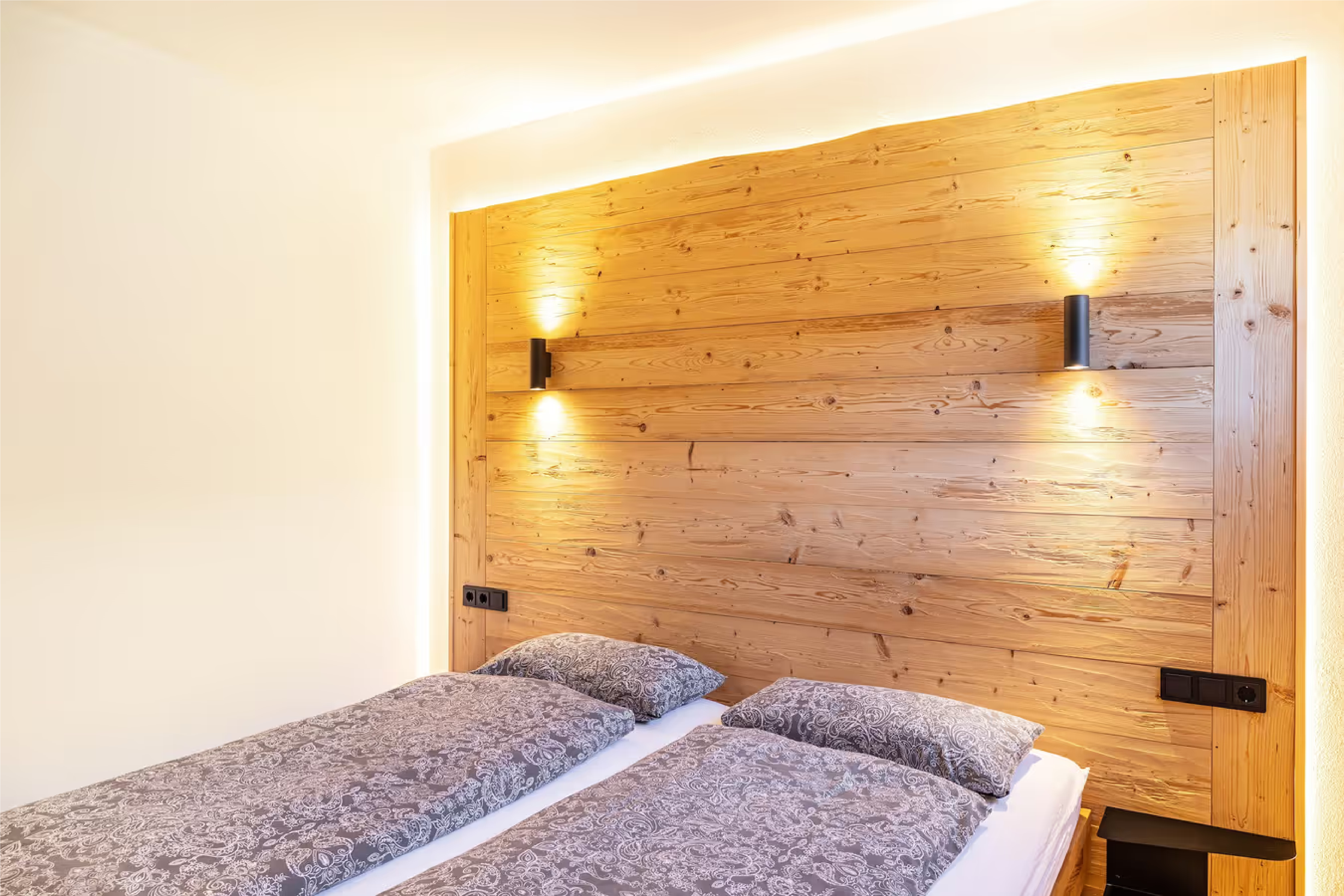 Bett mit warmem Holzkopfteil im Schlafzimmer der Ammerstube